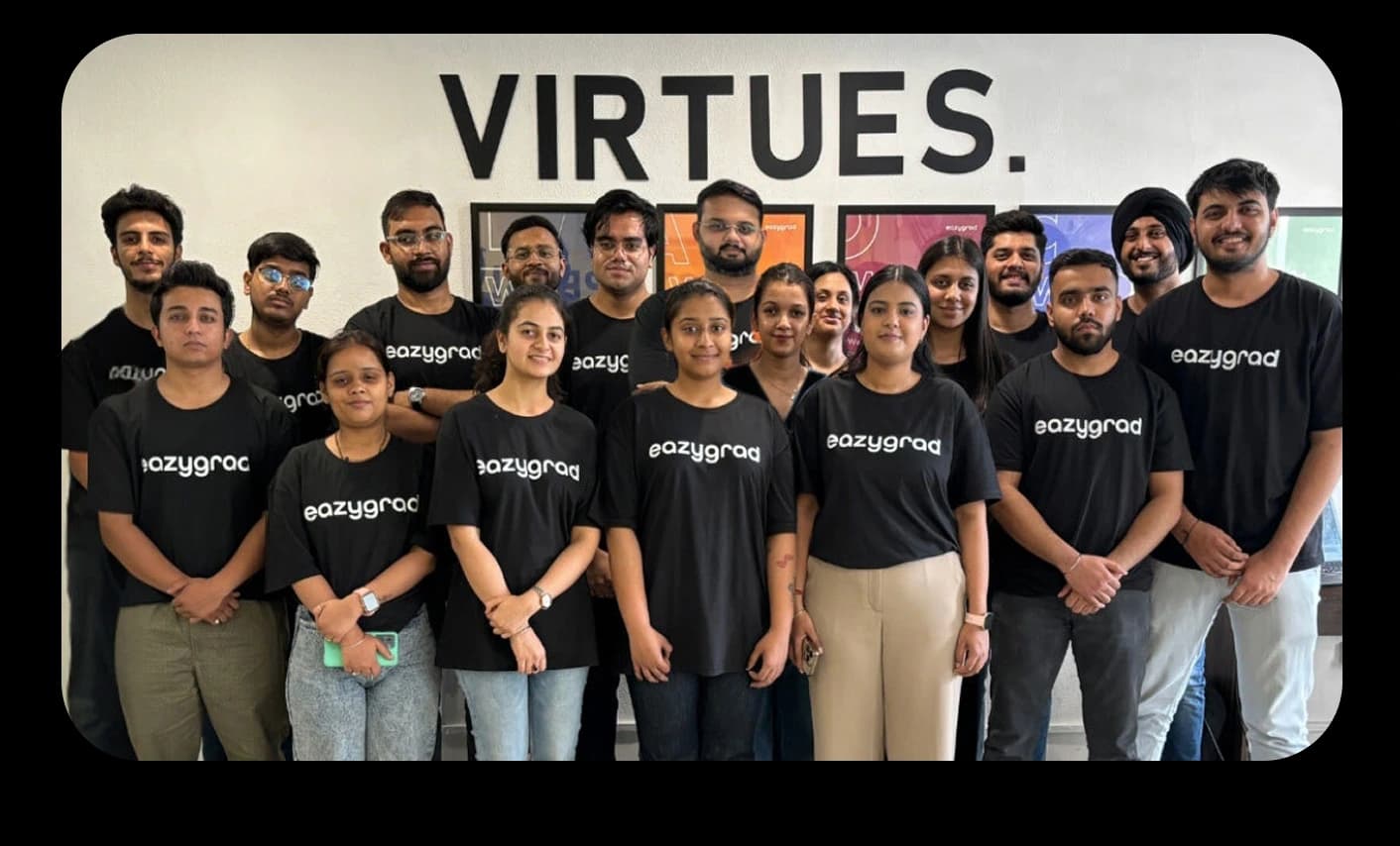 The EazyGrad team standing together in front of a wall reading VIRTUES.